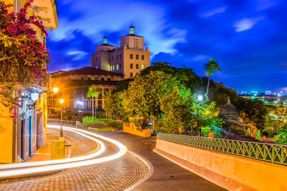 Night view of the cityscape and old ruins in san Juan with a car driving by in a blue in a long exposure image