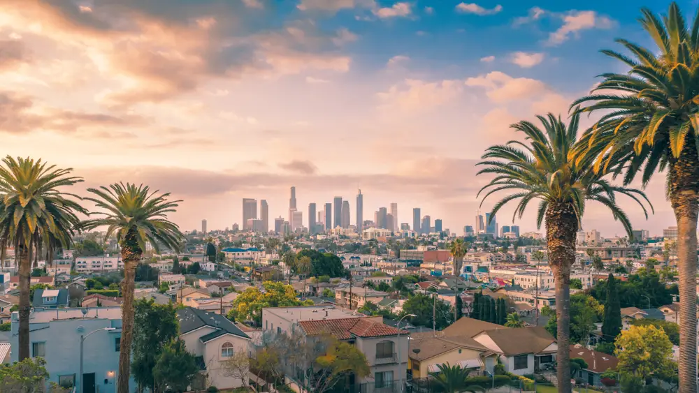 Los Angeles downtown skyline with palm trees and smog visible at sunset for a comparison between Northern and Southern California