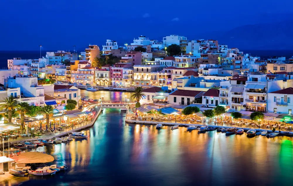 Agios Nikolaos lit up at night over the water near the harbor for a list showing the best Greek party islands to visit