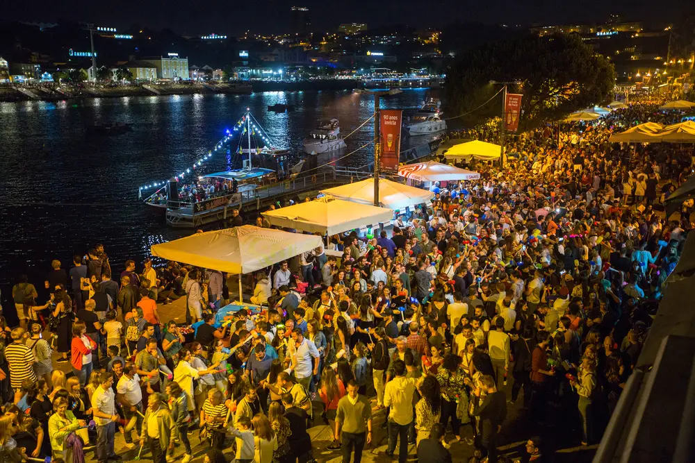 A large crowd is partying in the coastal area at night during a festival. 