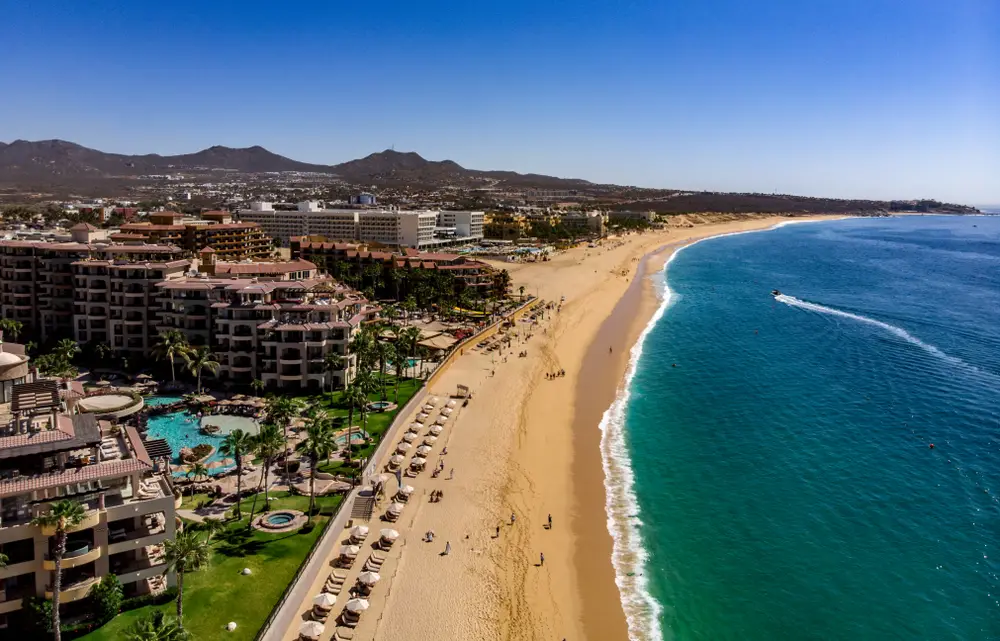 Aerial view of the best all-inclusive resorts for families in Cabo along Medano Beach in Cabo San Lucas with beach umbrellas set up on shore