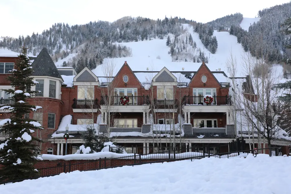 The front of a hotel covered with snow, with an icy hill in background. 