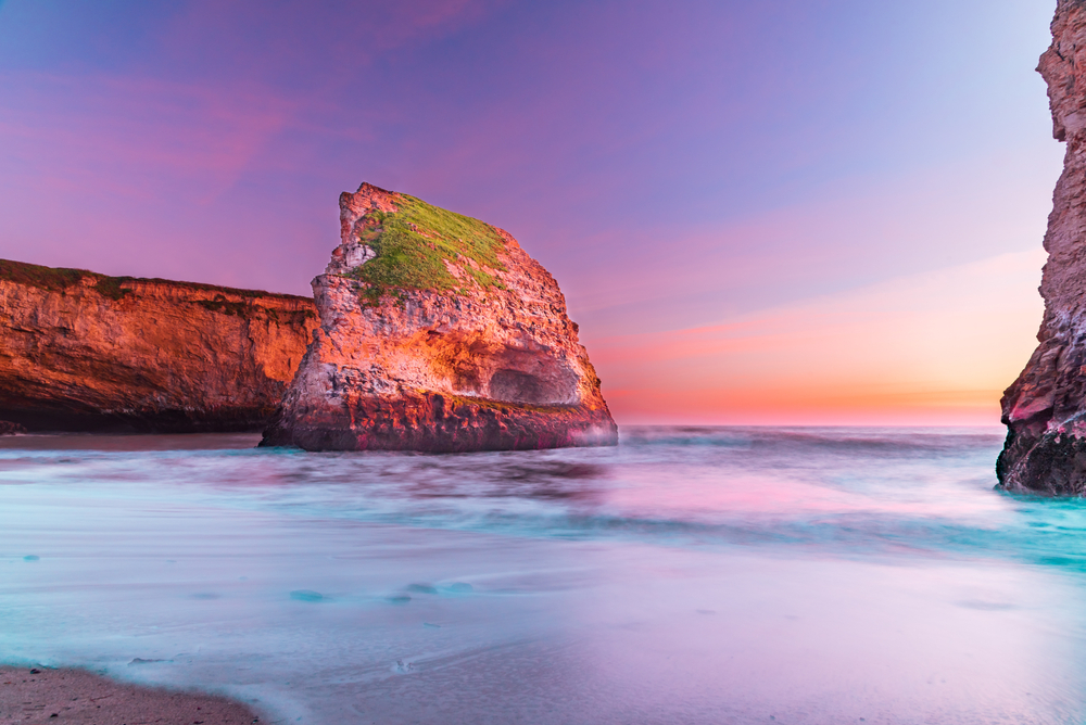 Shark Fin Cove pictured at dusk with foamy waves lapping the shoreline for a guide titled Where to Stay in Santa Cruz California