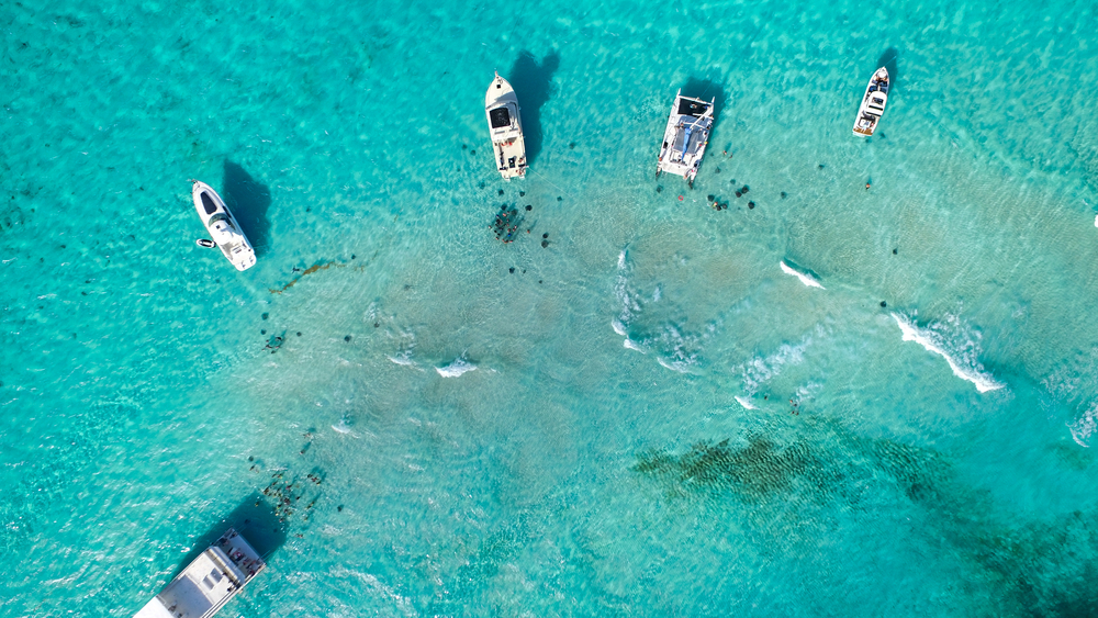 Aerial view on stationary five boats on shallow clear waters. 