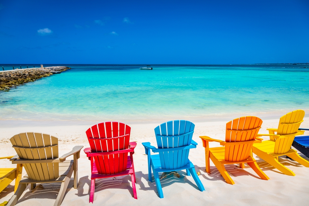 Ζωντανές ξύλινες καρέκλες σε μια ωραία λευκή παραλία έχουν θέα στην ήρεμη και καθαρή παραλία. 