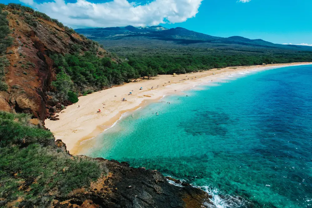 Aerial shot of the famous Big Beach in Maui with tourists set up on shore for a guide showing how long a flight to Hawaii takes from different places