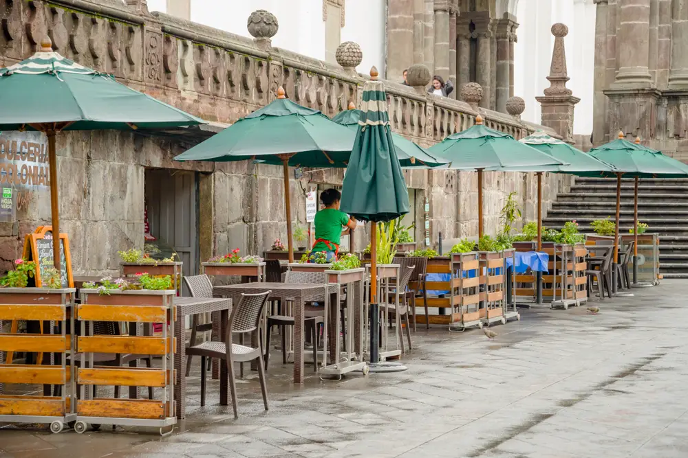 Ένα εστιατόριο στην άκρη του δρόμου με υπαίθρια τραπεζαρία καλυμμένη με πράσινες ομπρέλες. 
