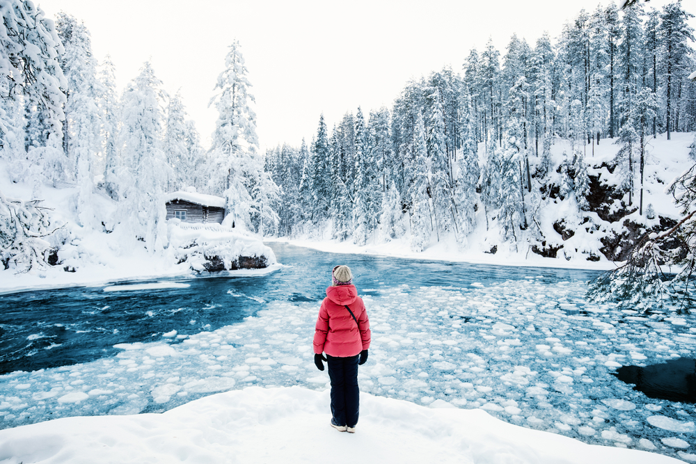 Ένα άτομο που στέκεται στην άκρη του πάγου και κοιτάζει την καμπίνα σε απόσταση, όπου τα πάντα γύρω είναι καλυμμένα με χιόνι.