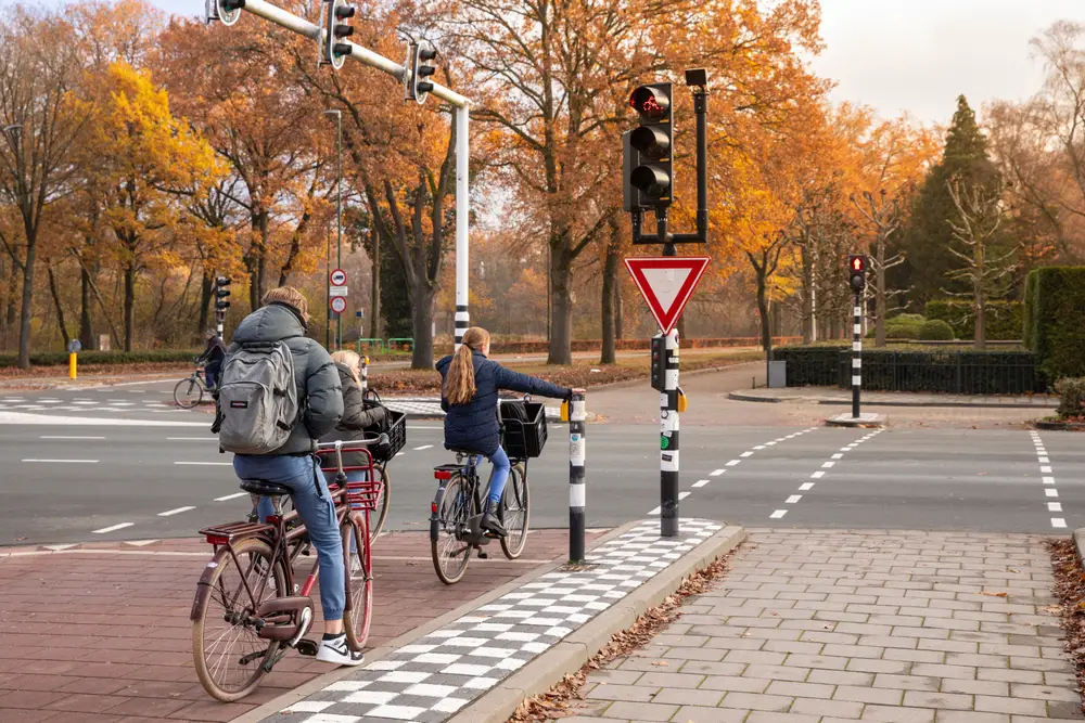 Τρία άτομα διακρίνονται να χρησιμοποιούν τον ποδηλατόδρομο, ενώ η πρώτη μπροστά της κάνει σήμα να πάει δεξιά χρησιμοποιώντας το χέρι της.