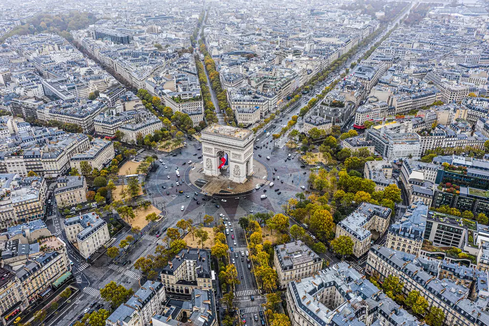 The famous Arc de Triomphe in Paris, France viewed from above, where is is located at the center and other buildings are surrounding it. 