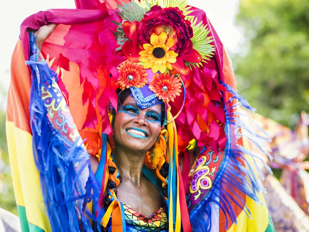 Μια γυναίκα που χορεύει σε ένα φεστιβάλ όπου φοράει ζωηρά ρούχα και μια φλοράλ κόμμωση.
