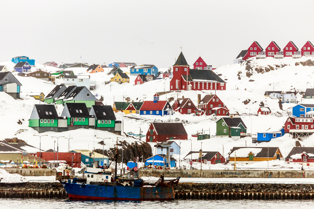 A coastal town covered with snow, and a boat can be seen docked on the pier.