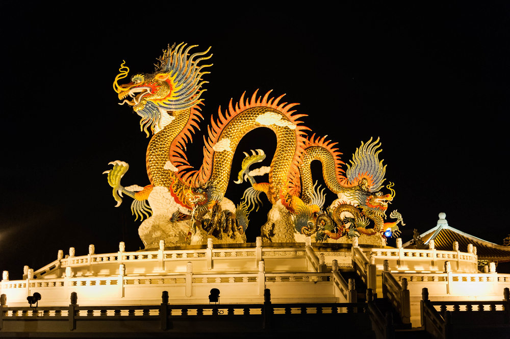 A Chinese dragon statue built at the center of a platform illuminated at night. 
