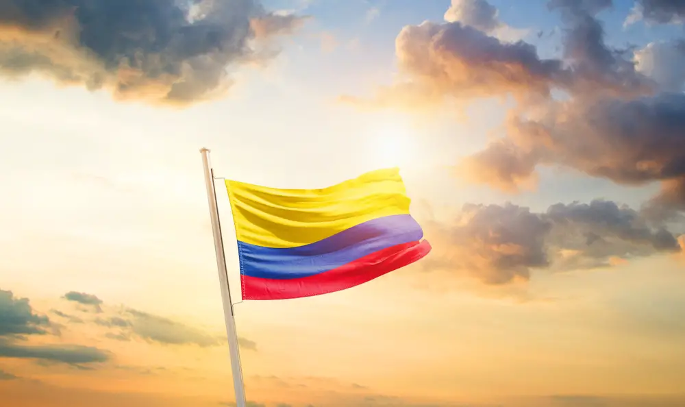 Η σημαία της Κολομβίας υψώνεται και κυματίζει σε έναν στύλο κατά τη διάρκεια του ηλιοβασιλέματος.