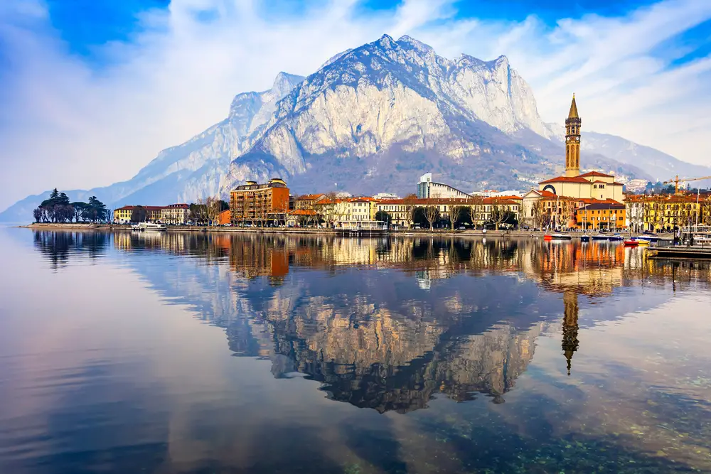 A beautiful image of a town and a mountain reflected on a calm lake.