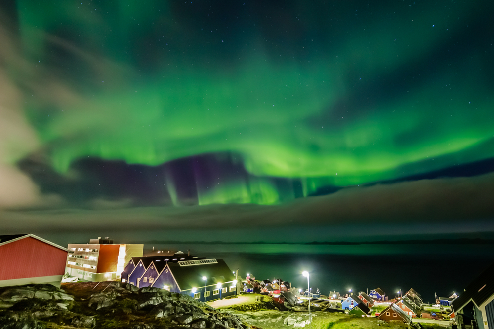 The majestic northern lights hovering above a town at night.