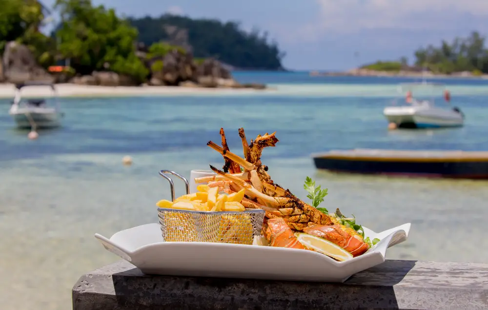 Ένα γεύμα που ετοιμάζεται σε ένα πιάτο με αστακό και πατάτες που τοποθετούνται σε ένα τσιμέντο κοντά στην παραλία.