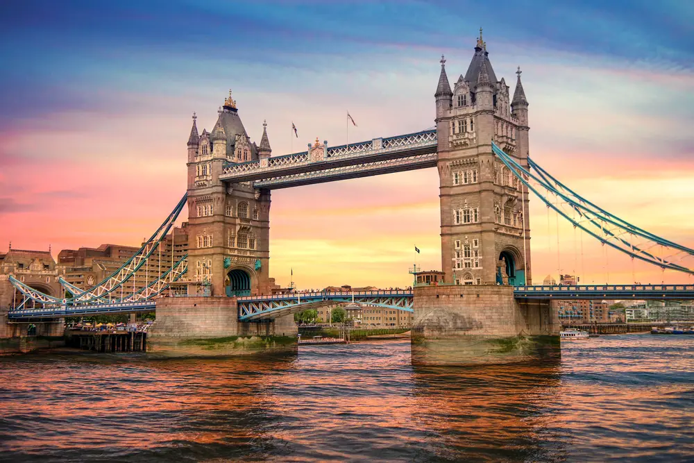 Η Γέφυρα του Πύργου του Λονδίνου παρουσιάζεται κατά τη διάρκεια ενός πολύχρωμου ηλιοβασιλέματος με ροζ και μπλε ουρανούς να αντανακλούν τον Τάμεση για έναν πλήρη οδηγό 2 εβδομάδων για την Ευρώπη που καλύπτει 3 κλασικές, εμβληματικές πόλεις