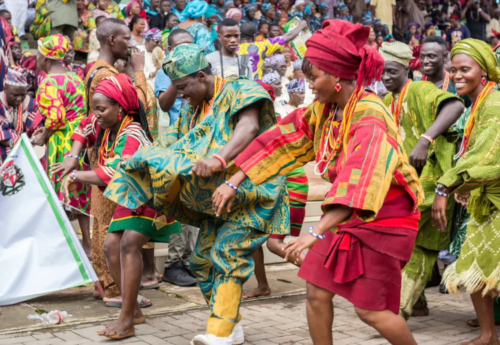 Οι ντόπιοι φορούν ρούχα με πράσινα και κόκκινα σχέδια ενώ χορεύουν ξυπόλητοι στους δρόμους κατά τη διάρκεια ενός φεστιβάλ.