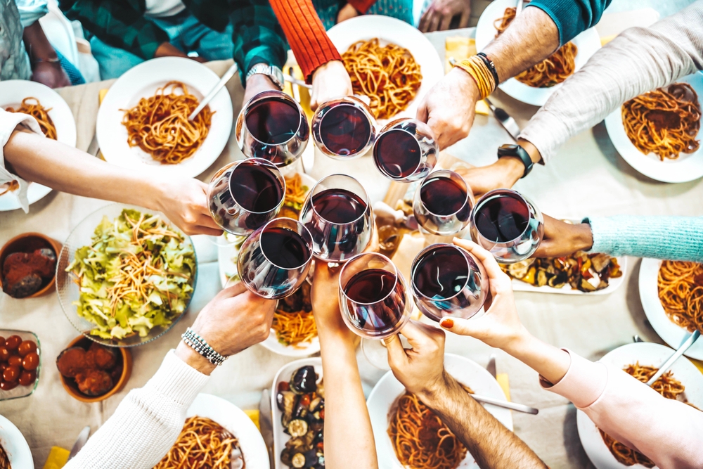 Μια παρέα φίλων που σηκώνουν τα ποτήρια κρασιού τους προς το κέντρο για ένα τοστ και το φαγητό φαίνεται παρακάτω. 