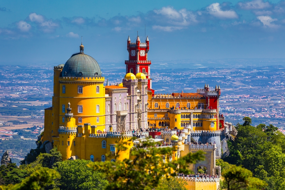 Colorful Palace of Pina sits on a hilltop in Sinta, Portugal to show how this country has a vibrant culture and beautiful architecture in a comparison with Spain