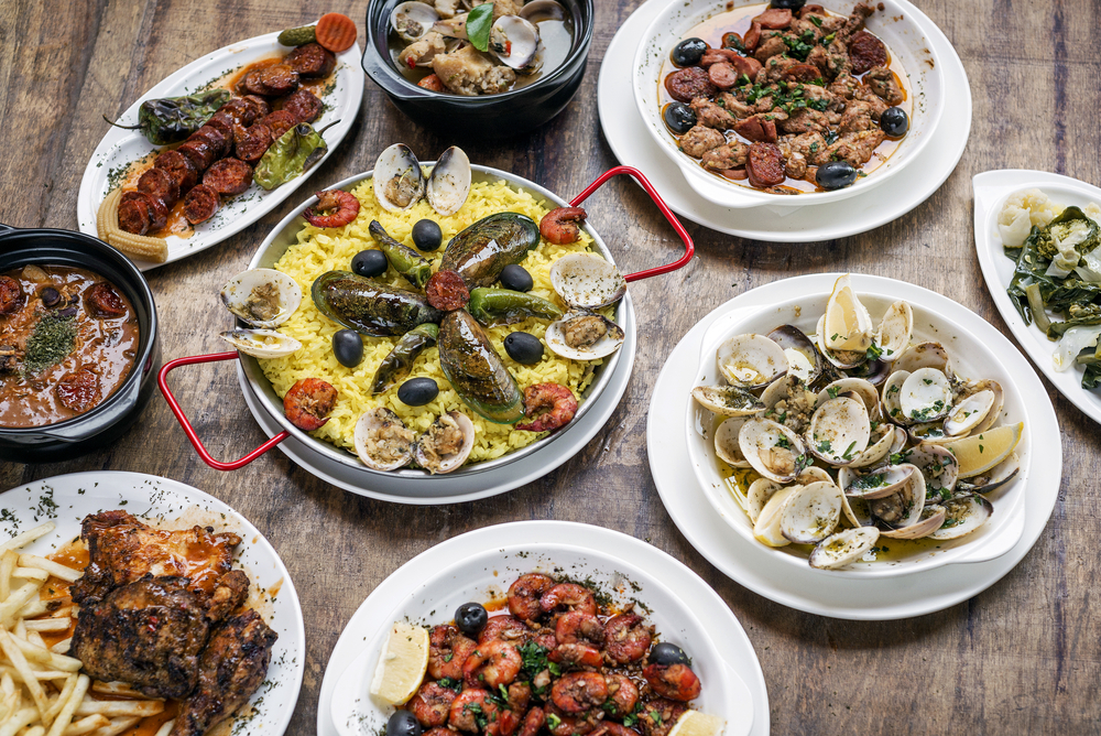 View looking down at a table filled with plates of traditional Portuguese foods laid out attractively for a piece showing the differences between Portugal and Spain