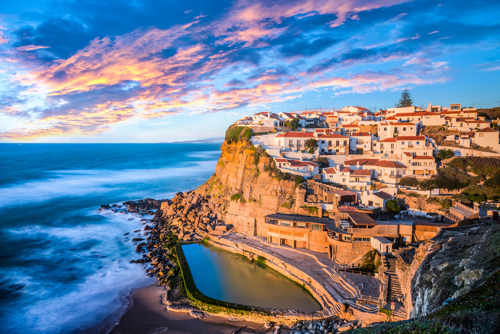 Azenhas do Mar in Sintra, Portugal during a colorful sunset by the water for an FAQ section showing the contrast of Spain vs Portugal