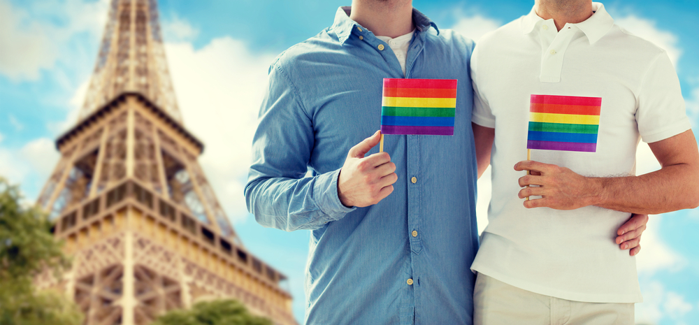 Δύο άνδρες που κρατούν μια μικρή σημαία LGBT ενώ στο βάθος είναι ο Πύργος του Άιφελ.