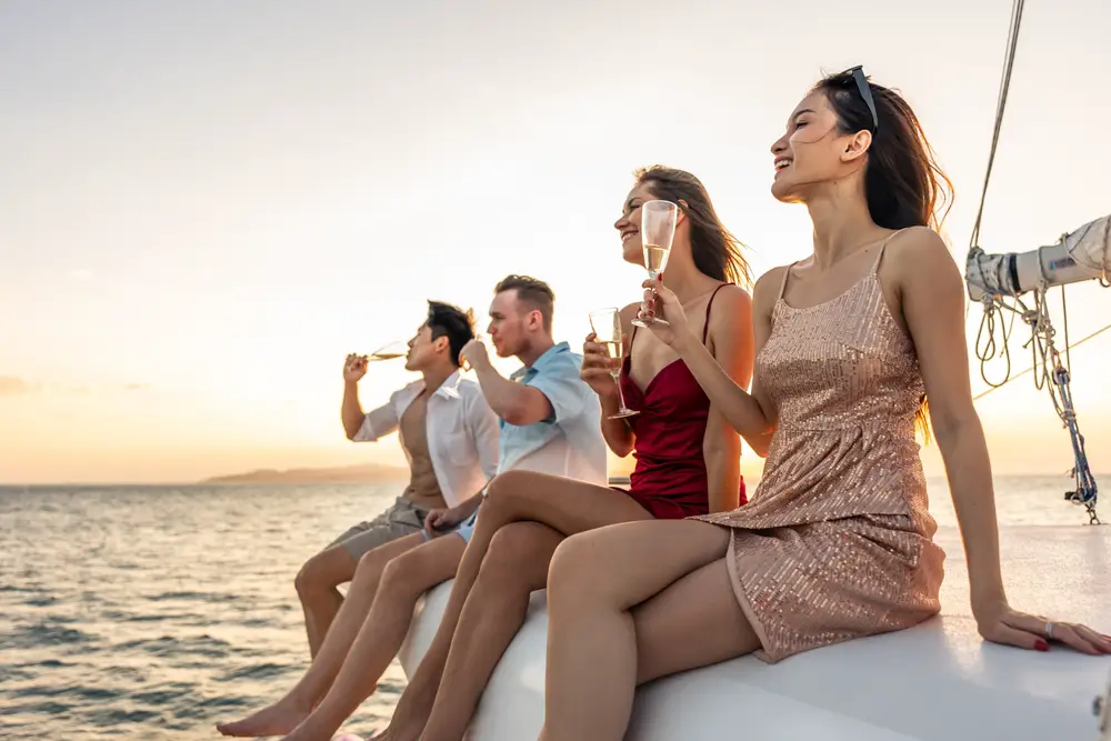 Μια ομάδα φίλων που κάθεται στο τέλος μιας βάρκας πίνοντας κατά τη διάρκεια του ηλιοβασιλέματος.