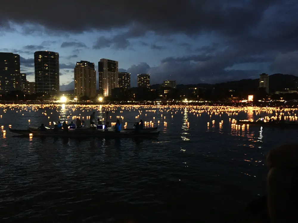 The Honolulu Lantern Festival seen at dark with lights glowing on the surface of the water for a frequently asked questions section on the number of people living in Hawaii overall