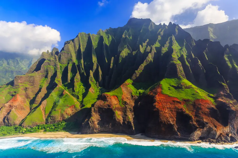 Η ακτή Napali στο Kauai παρουσιάζεται με απόκρημνα βουνά και γαλάζια νερά κάτω σε μια ωραία καθαρή μέρα για οδηγό που δείχνει πότε η Χαβάη έγινε πολιτεία το 1959 με πλήρες χρονοδιάγραμμα