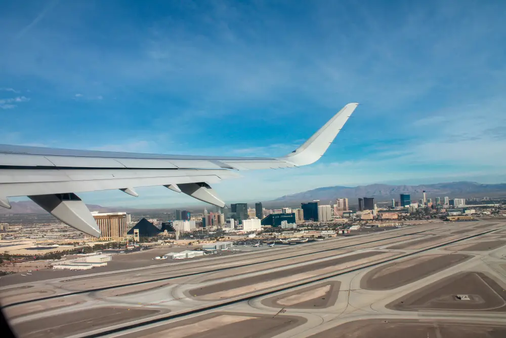 Αεροπλάνο που φεύγει από το αεροδρόμιο MaCarran στο Λας Βέγκας με θέα τα κτίρια σε απόσταση για ένα άρθρο που συζητά πόσο διαρκεί μια πτήση προς Βέγκας;