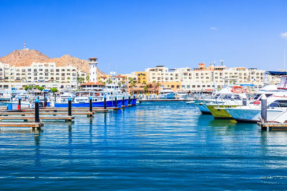 Μαρίνα στο Κάμπο με πολλά πολύχρωμα σκάφη που πλαισιώνουν το λιμάνι για έναν οδηγό με τίτλο Is Cabo Safe to Visit