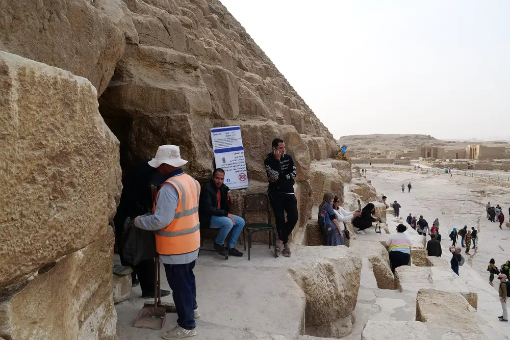 Είσοδος της πυραμίδας όπου διακρίνονται μερικοί άνθρωποι να στέκονται στο πλάι της κατασκευής. 