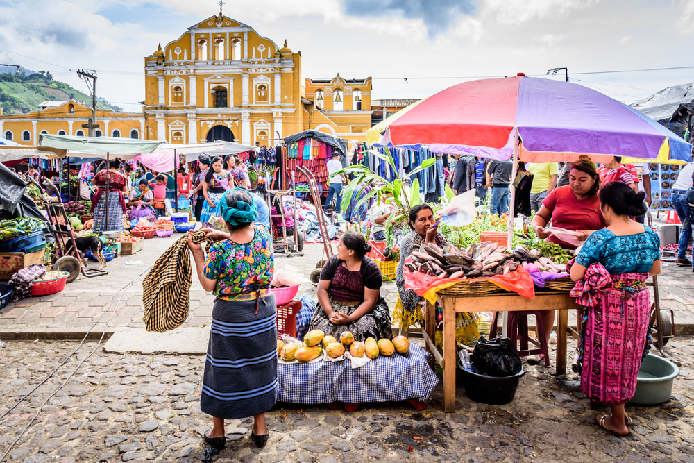 Αγορά στην Αντίγκουα που απεικονίζεται για έναν οδηγό με τίτλο Is Guatemala safe to visit with the Santa Maria de Jesus αγορά στη μέση ενός πολύχρωμου πλήθους