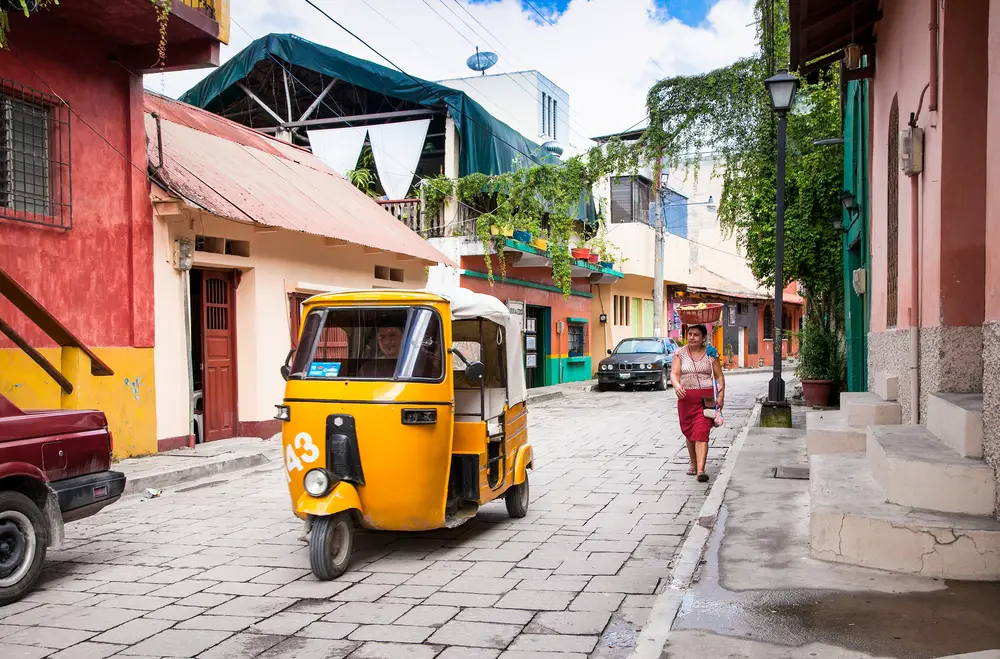 Κίτρινο ταξί σε στυλ τουκτούκ που απεικονίζεται σε έναν δρόμο από τούβλα στο Flores της Γουατεμάλας