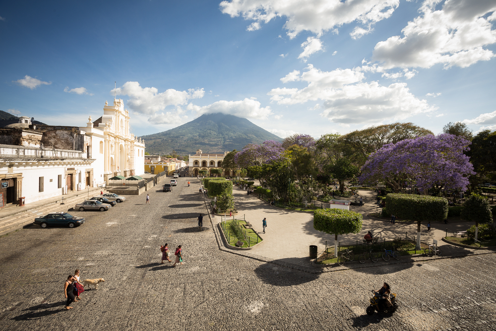 Τοποθεσία στο κέντρο της Αντίγκουα για ένα κομμάτι σχετικά με το εάν η Γουατεμάλα είναι ασφαλής για επίσκεψη με ένα γιγάντιο ηφαίστειο που δεσπόζει πάνω από μια λευκή πέτρινη πόλη