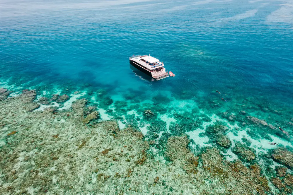 Αεροφωτογραφία ενός καταδυτικού σκάφους πάνω από τον Μεγάλο Κοραλλιογενή Ύφαλο που απεικονίζεται κατά τη διάρκεια της άνοιξης, η καλύτερη εποχή για να επισκεφθείτε