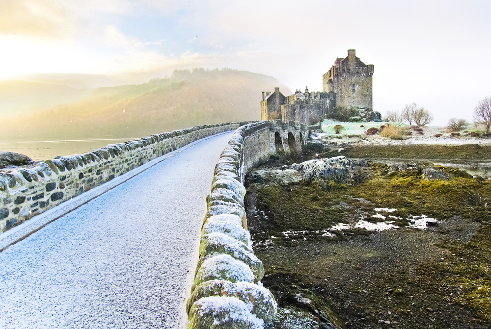 Στη φωτογραφία κατά τη λιγότερο πολυάσχολη περίοδο για να επισκεφθείτε το Ηνωμένο Βασίλειο, τον χειμώνα, το Κάστρο Eilean Donan απεικονίζεται με χιόνι ολόγυρα και έναν πορτοκαλί ουρανό πίσω του
