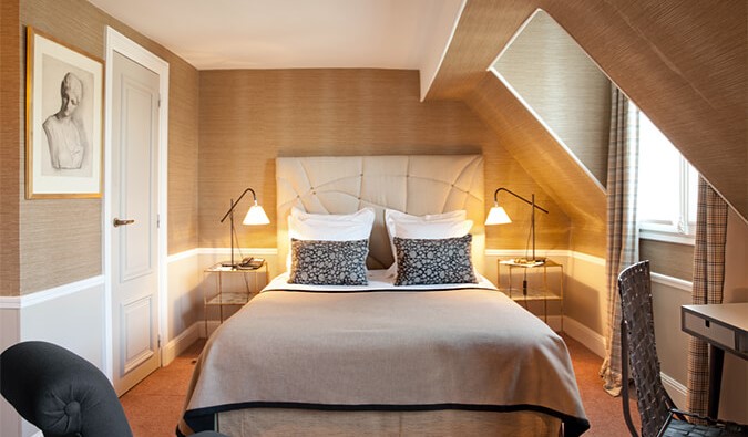 Ένα άνετο δωμάτιο ξενοδοχείου με κρεβάτι queen size, απαλό φωτισμό, πίνακα ζωγραφικής στους τοίχους και παστέλ χρώματα σε όλο το Παρίσι, Γαλλία