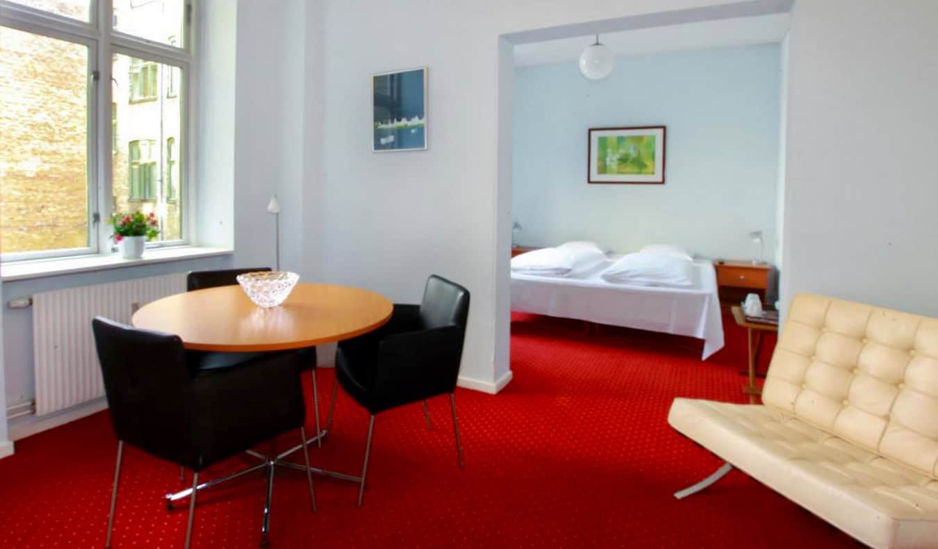 Ένα ευάερο και ευρύχωρο δωμάτιο ξενοδοχείου με έντονο κόκκινο χαλί στο Hotel Nora στην Κοπεγχάγη της Δανίας