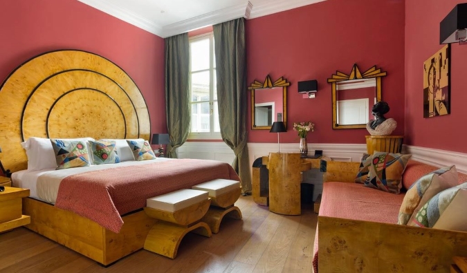Ένα δωμάτιο ξενοδοχείου με ζωντανούς τοίχους στο χρώμα του σολομού και ένα κρεβάτι, γραφείο και καθρέφτες σε ένα funky ξύλινο στιλ Art Deco στο La Maison du Sage, ένα ξενοδοχείο στη Φλωρεντία της Ιταλίας