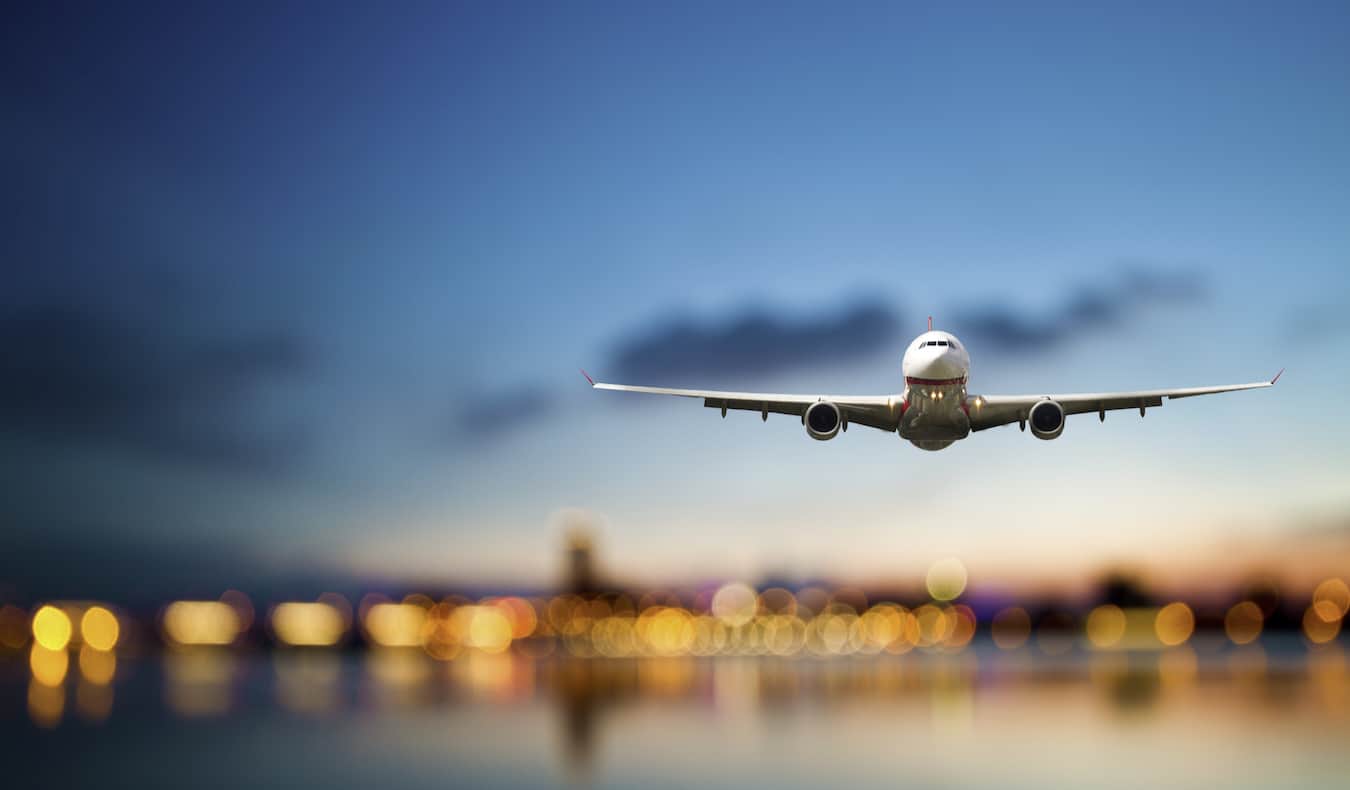 Ένα τεράστιο εμπορικό αεροσκάφος που πετά μέσα από το σκούρο μπλε ουρανό καθώς έρχεται για προσγείωση σε ένα αεροδρόμιο