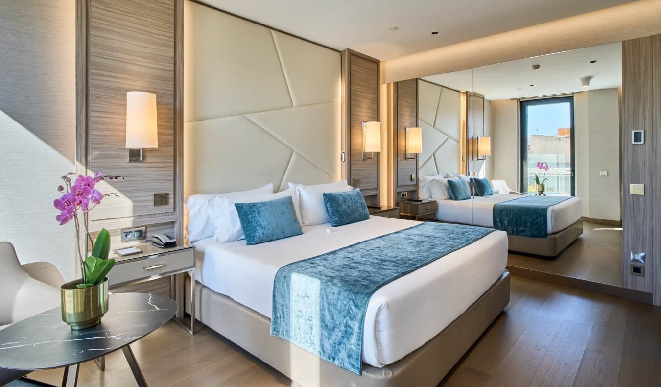 Ένα king size κρεβάτι σε ένα δωμάτιο ξενοδοχείου με μοντέρνο ντιζάιν, έναν μεγάλο καθρέφτη και ορχιδέες στο τραπέζι στο VP Plaza España Design στη Μαδρίτη, Ισπανία